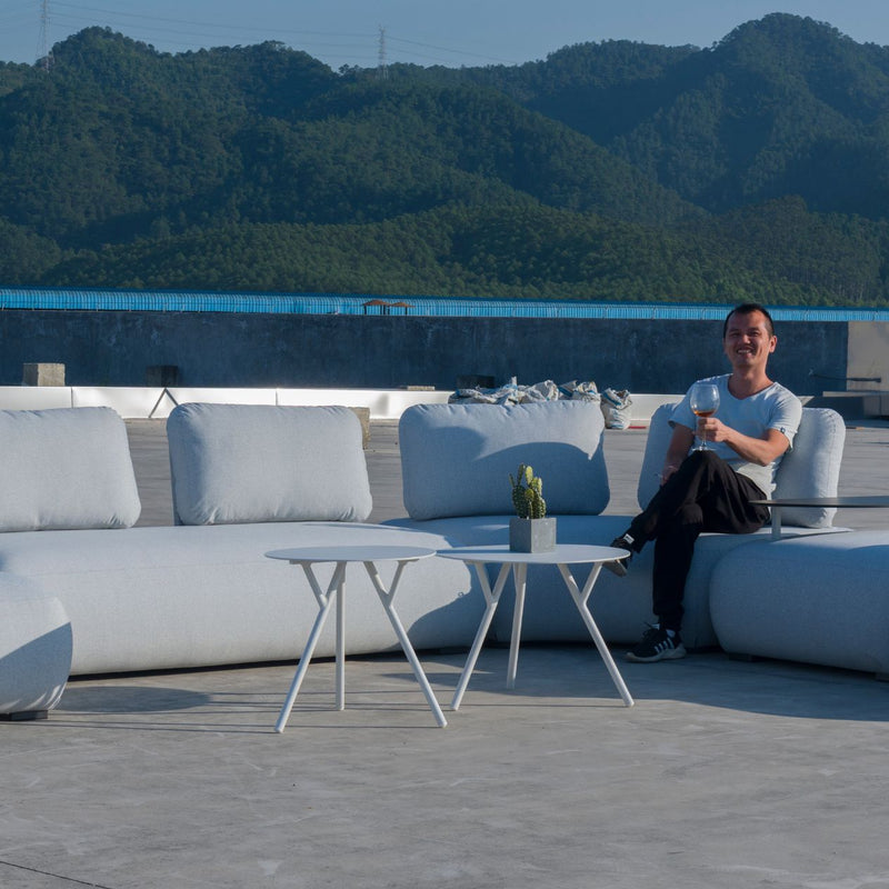 Outdoor furniture set featuring two aluminium round coffee tables with light grey frames, paired with an upholstered modular lounge set outdoors. Experience style and functionality with the Iowa coffee table.