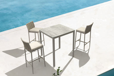 Chic white and cream barstools arranged around a table in an outdoor resort space, suitable as luxury bar furniture & luxury balcony furniture.