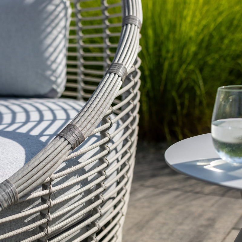 Close-up of the Peninsula Outdoor Wicker Daybed by Couture Jardin, highlighting its high-quality woven wicker frame and durable Couturetex textile cushions in light gray. The intricate weave and reinforced binding showcase the craftsmanship, while the water-resistant fabric ensures longevity.