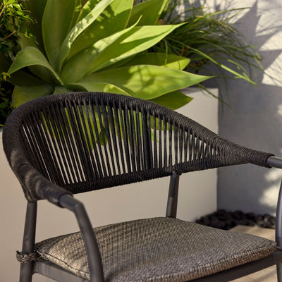 Outdoor furniture: The Windsor Dining Chair, a rope chair with charcoal frame and fabric, set outdoors with plants.