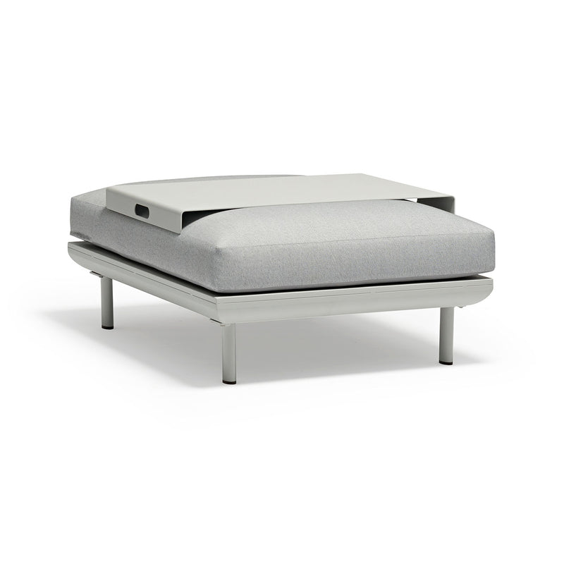 A sleek light grey ottoman with an aluminum frame, set against a plain white background, featuring a small aluminum plate on top.