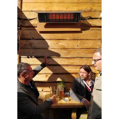 Three bar goers enjoying warmth from a Heatscope heater overhead, set against a wooden bar wall in an outdoor living space.