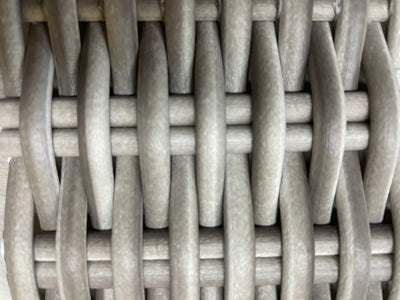 Closeup of the white wicker material of an outdoor sofa.