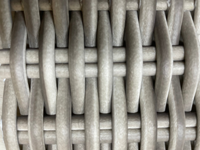 Closeup of the white wicker material of an outdoor sofa.